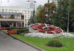 Клумба в виде часов гранитная облицовка, посадка декоративных растений, газон у здании преффектуры Юго Западного округа г.Москва.